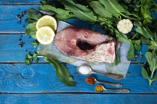 Bistecca di pesce crudo su carta con erbe aromatiche, spezie e limone su bac blu — Foto Stock