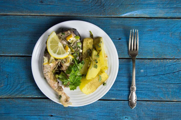 Bife de peixe frito em um prato com batatas, limão, verdes. Servido — Fotografia de Stock