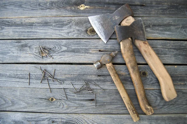Två yxor, hammare och spik ligga på träskivor — Stockfoto