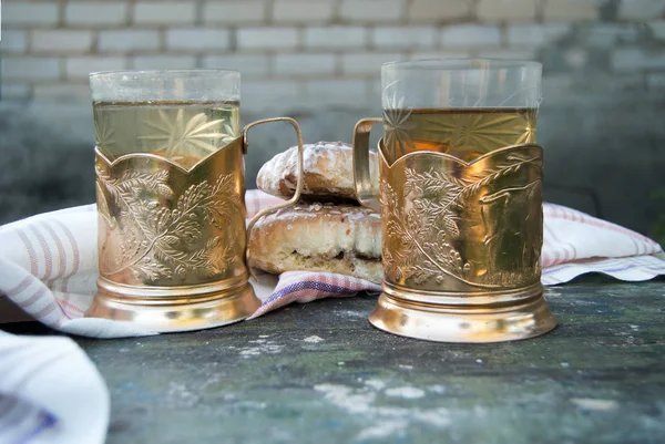 Twee kopjes thee in glazen met bekerhouders en taarten — Stockfoto