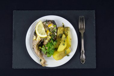 Limon ve bir beyaz tabakta çatal ile kızarmış patates balık biftek