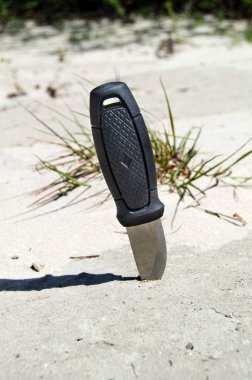 Siyah saplı bir av bıçağı kuma sıkıştı