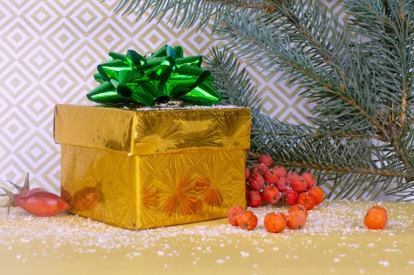 Cadeau emballé dans une boîte en or. Composition avec branches de sapin, bois rouge — Photo