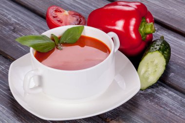 Ahşap arka plan üzerinde beyaz bir tabak içinde domates, biber ve salatalık soğuk çorba