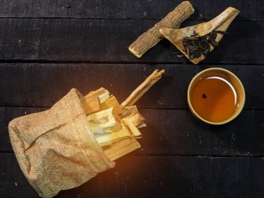 Ahşap ahşap masa, bulanık ahşap ot sopa kenevir çanta yanında Kupası ve kuru çay yaprakları kil Çin tra seçici odak içinde koymak.