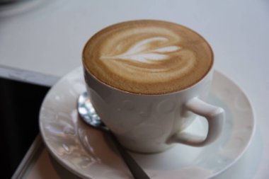 Cuppuccino kahve Kupası krem köpük kalp resim seçici tablo ve kahve barı, etrafında bulanık ışık koymak.