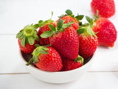 Ahşap masa, etrafında bulanık ışık koymak büyük kase kırmızı çilek.