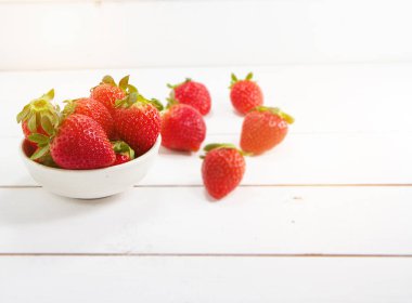 Ahşap masa, etrafında bulanık ışık koymak kırmızı çilek.