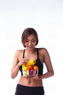 Siyah egzersiz elbiseli Bayan karışık taze meyve kase tutarak ve meyve ile mutlu seçme ve face.apple, portakal ve Mısır kase, sağlıklı gülümseme ve meyve diyet