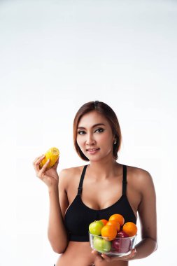 Egzersiz elbiseli Bayan sol el ve sarı ile tutun karışık frruit kase gülümseme ve mutlu face.green elma, kırmızı elma ile onun sağ elinde, portakal vardır kase, sağlıklı meyve, diyet için iyi