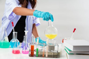 Bayan mavi kauçuk eldiven ile Beyaz üniformalı, kimyager tarafından test tüpü ile reaktif laboratuarında çalışıyor