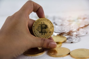 Altın bitcoin seçici odak içinde insan elle etrafında bulanık ışık tutuyordu