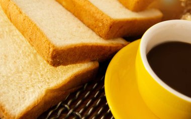 dilimlenmiş ekmek yarısı sarı seramik kahve Kupası, vintage ve sanat tarzı koymak, hafif sesi, etrafında bulanık ışık sıcak.