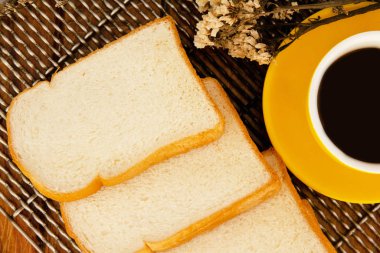 Dilimlenmiş ekmek yarısı sarı seramik kahve Kupası, vintage ve sanat tarzı koymak, hafif sesi, etrafında bulanık ışık sıcak.