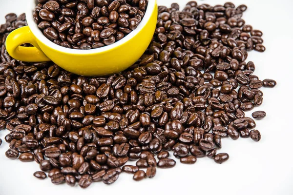 The roasted coffee beans put in ceramic cup among group of coffee beans on white background,blurry light around.