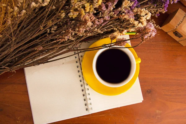 本と黄色のセラミック コーヒー カップ入れて乾燥花 ヴィンテージ スタイルの横にある 木製の机の上暖かい光のトーン バリーのライト周り — ストック写真