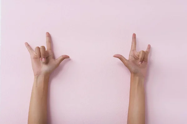 The humand hands raise up on pink pastel background and show Love Hand Sign,th3 hand sign of togetherness,partnership of human,union,the symbol of love