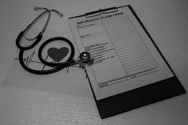 Stethescope 用心率波形图和小心脏在保险理赔表上 用黑白相间的语气 — 图库照片