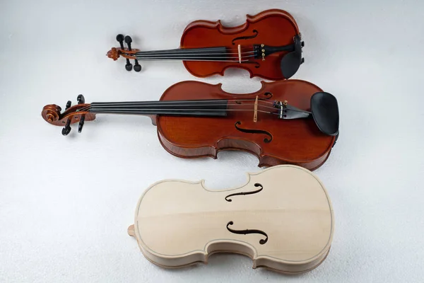 Violino cru colocado na frente de dois violinos completados — Fotografia de Stock