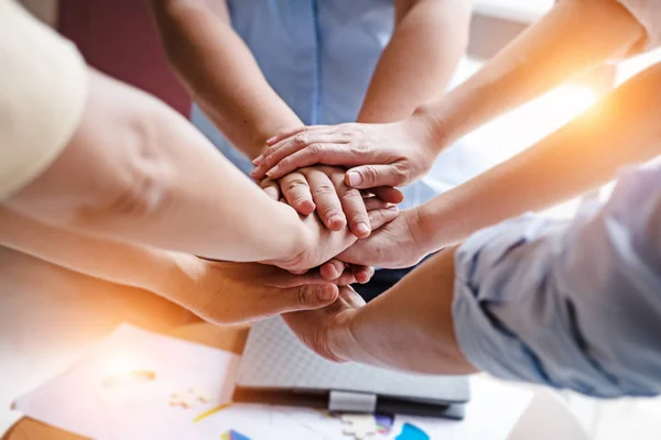 In selective focus of human hands stacked together,Business group,Hands together joining teamwork concepts,Collaborate project,blurry light around.
