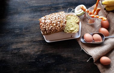 Tam buğday ekmeği, ekmek çubuğu ve yumurtalar ahşap masanın sağ tarafına konur.,