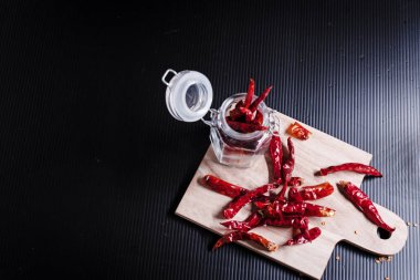 Tahta tepsiye konulan kurutulmuş biber grubu, siyah tahtanın sağ tarafında,