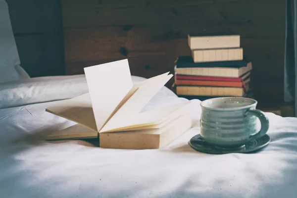 セラミックコーヒーカップの抽象アートデザインの背景とオープンブックは ヴィンテージとアートトーンでベッドに置かれました — ストック写真