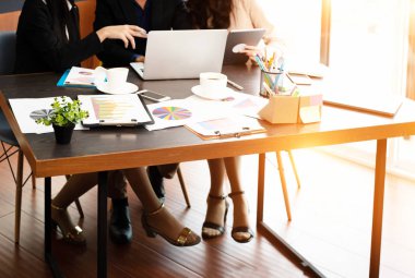 İş işçileri ofis saatinde çalışıyor, masadaki iş kağıdı grafiği bol, toplantı zamanı, sıcak ışık tonu, bulanık ışık