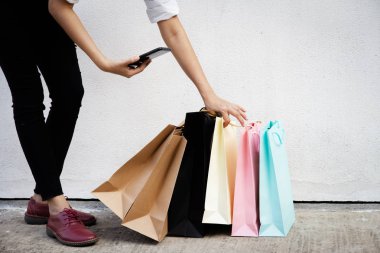 Alışveriş poşetleri kadın çılgın alışverişkolik el tarafından toplanıyor, ve cep telefonu tutun, alışveriş merkezinde.renkli kağıt alışveriş torbaları.