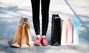 Alışveriş merkezinde kadın çılgın alışverişkolik kişinin yanına konulan alışveriş çantaları.renkli kağıt alışveriş poşetleri.