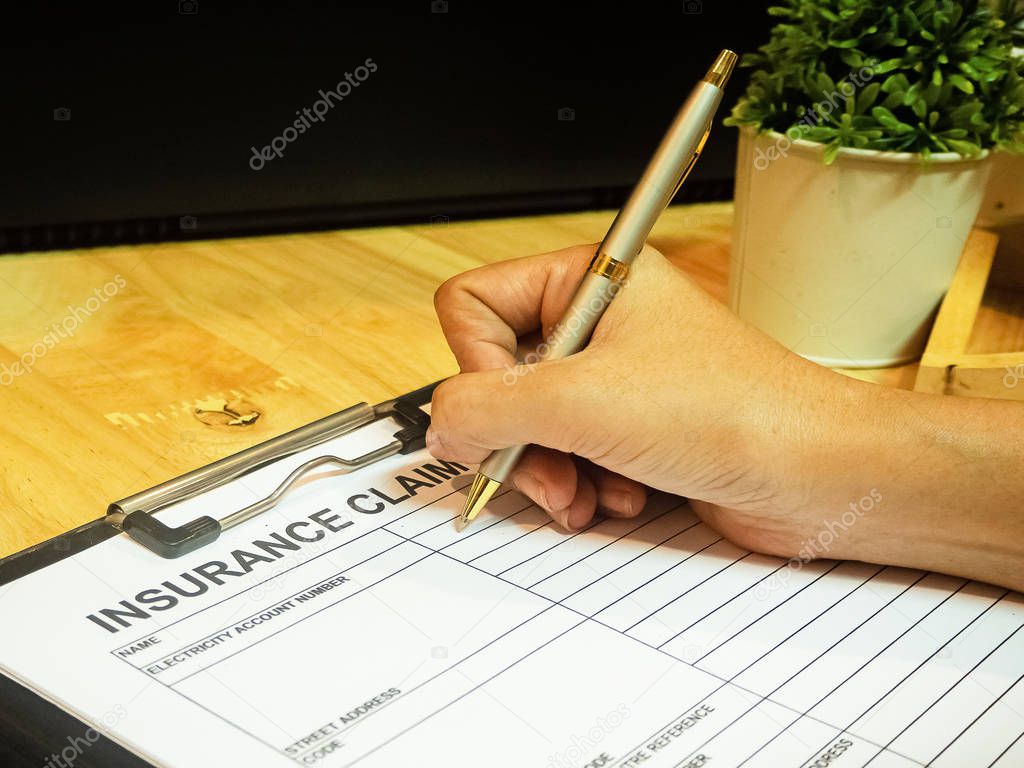 The human hand is using pen for filling the information on Insurance Claim Form