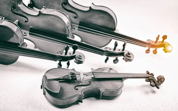 The smallest size of violin put in front of the other size of violin,on background,show detail of instrument