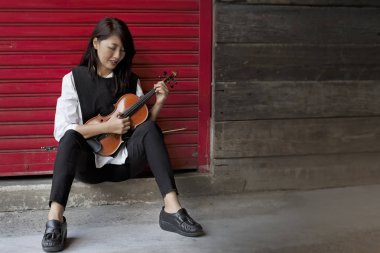 Wihte gömlek ve siyah kot giyen güzellik bayan seçici odak, keman dizeleri koparmak için parmak kullanın, Pizzicato Tekniği, etrafında şişkin ışık