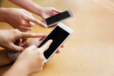 Cep telefonunun ekranını gösteren insan elleri, bulanık ışık.