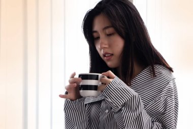 Elinde seramik kahve fincanı tutan güzel kadının seçici odağında, içkiye hazırlanın, dinlenme zamanı, bulanık ışık