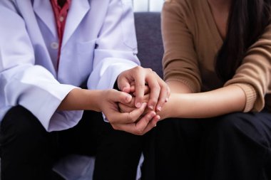 Doktor ellerinin hasta ellerini tutan seçici odağında, zihin iyileşmek için cesaretlendirme ve teselli.bulanık ışık