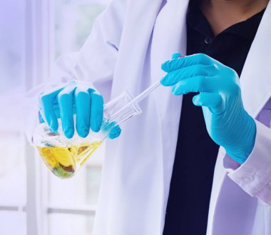 Bilim adamı cam pul için sıvı madde bırakarak, Lab test çalışma, yeni ürün için araştırma, bulanık ışık etrafında