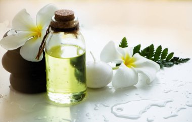 Aromagheraphy masaj yağı siyah kaya spa yanında koymak, mum ve çiçek, arka planda spa terapisi