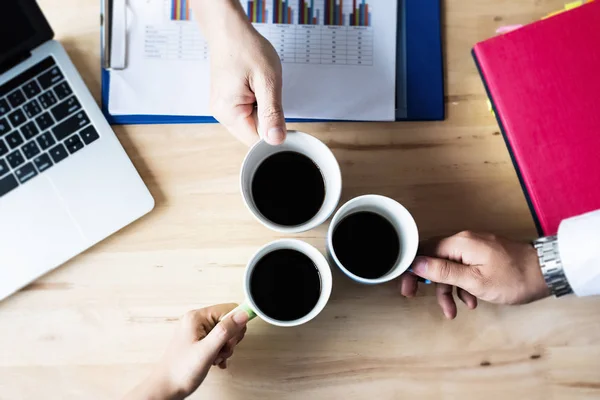 Three coffee cups was holding by hands of business worker,coffee break between working at office,blurry light around