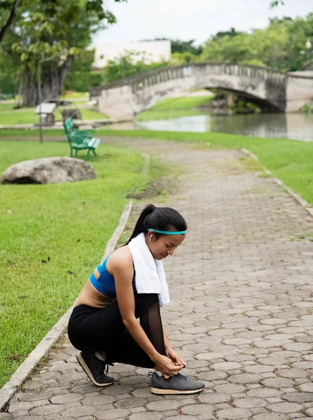 Woman wearing exercise suit ,tie shoelaces ,prepare for jogging in a park