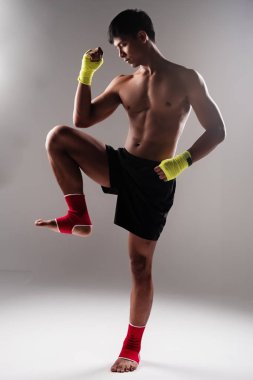 Sarı eldiven ve kırmızı bilek giyen yakışıklı adam, elini kaldır ve yumruk, dizini kaldır, Tayland boks desenini göster.