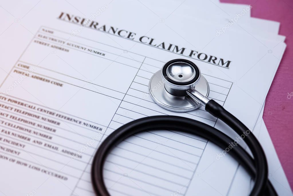 Head of stethoscope put on blurred insurance claim form,on background,blurry light around