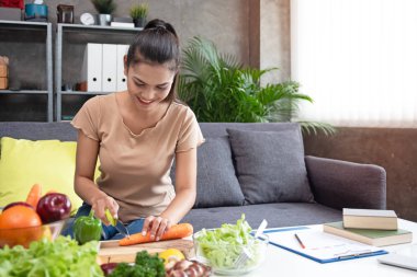 Tahta tepside güzel bir havuç kesme, gülümseme ve mutluluk, salata yemeği hazırlama, taze sebze ve diyet planı masaya konur, bulanık ışık yayılır.