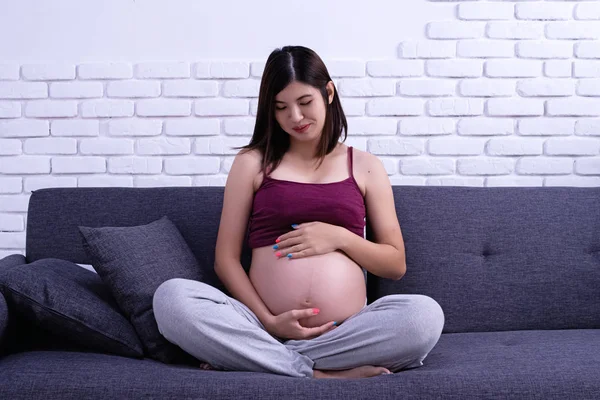 Kobieta Ciąży Siedzi Kanapie Kładzie Rękę Dotykając Jej Brzucha Miłością — Zdjęcie stockowe