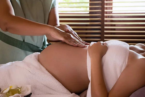 Spa terapisindeki tedavi ve rahatlama programı için hamile bir kadına masaj yapan terapist elleri.
