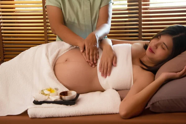 Spa terapisindeki tedavi ve rahatlama programı için hamile kadına masaj yapan terapist.
