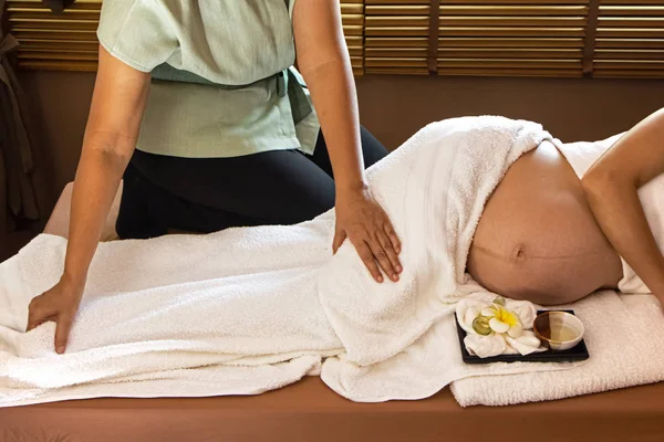 Spa terapisindeki tedavi ve rahatlama programı için hamile kadına masaj yapan terapist.