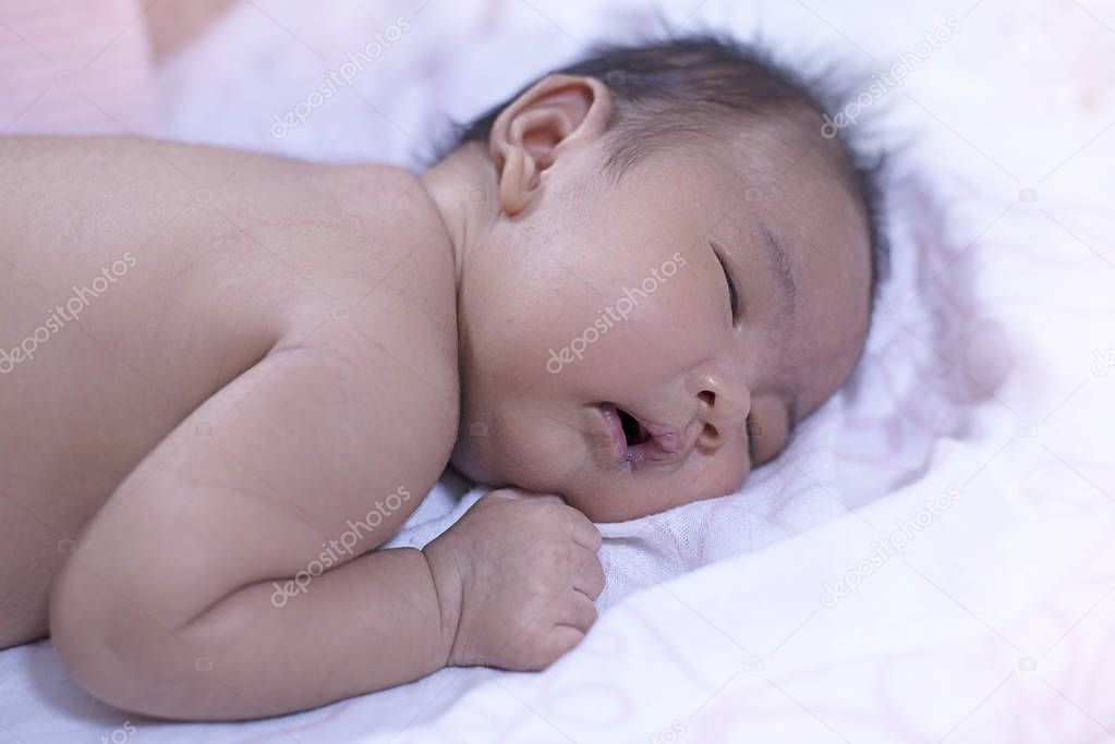 The newborn baby sleeping,closed eyes and opened small lip,blurry light design background
