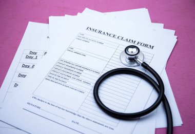 Steteskop sigorta talep formunun yanına koyulmuş, arka planda, bulanık ışık var.