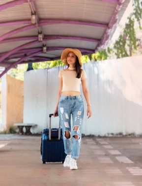 Yolculuk için bavul taşıyan güzel kadın, mutlu bir şekilde, bulanık bir ışıkla.